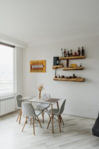 Bright dining room with minimalist design, featuring wooden shelves and large window.